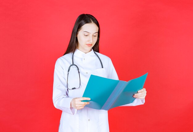 Doctor with a stethoscope holding the history of the patient and verifying it.