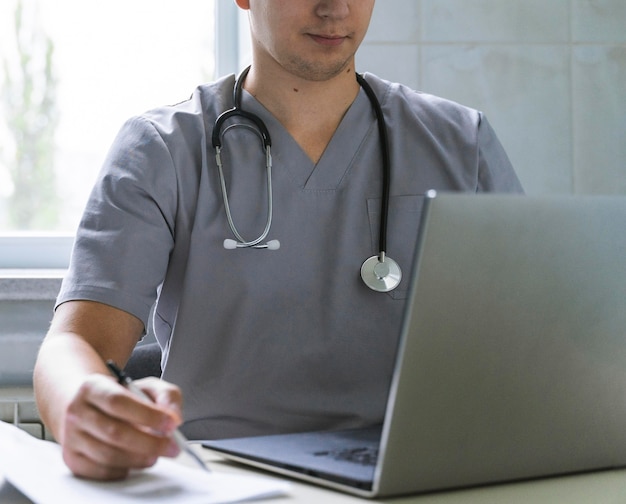 Doctor with stethoscope working on laptop