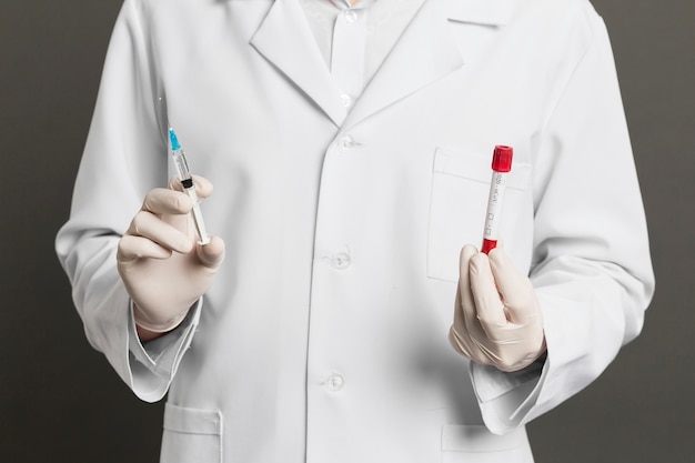 Doctor with surgical gloves holding syringe and vacutainers