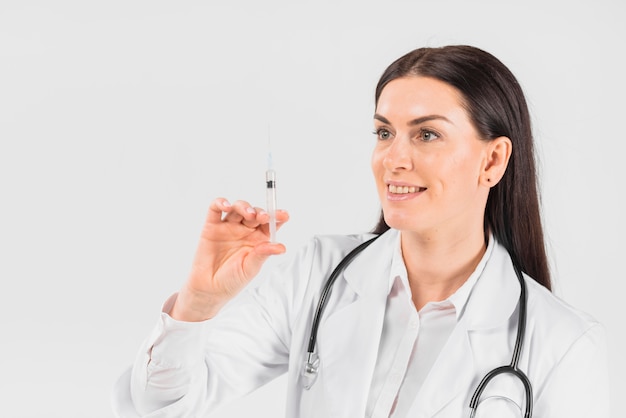 Doctor woman holding and looking at syringe