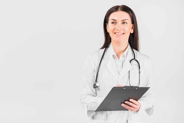 Free photo doctor woman smiling, holding clipboard and looking away