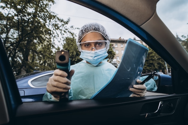 Foto gratuita la donna del medico usa la pistola del termometro a infrarossi per controllare la temperatura corporea