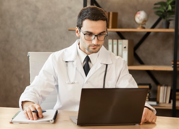 Doctor working on laptop medium shot