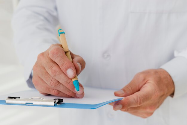 Doctor writing on clipboard close-up