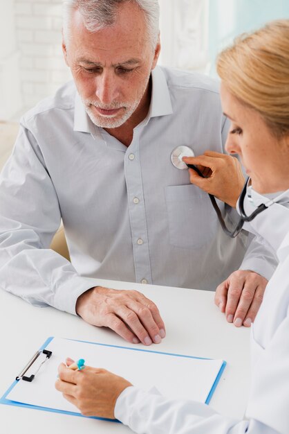 Doctor writing on clipboard while auscultating