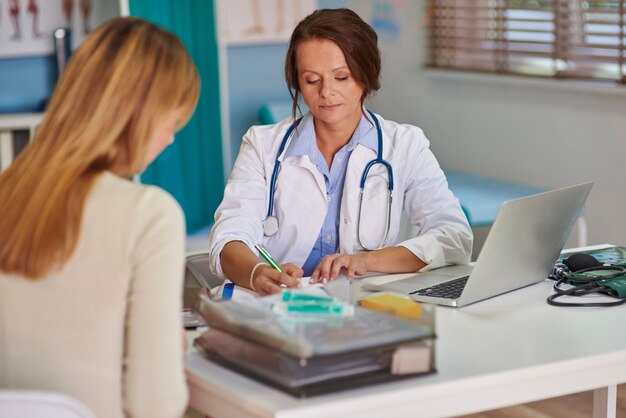 Doctor writing a prescription for her patient