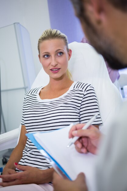 Doctor writing on reports while discussing with patient