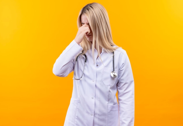 의료 가운에 청진기를 입고 의사 어린 소녀 격리 된 노란색 벽에 코를 폐쇄