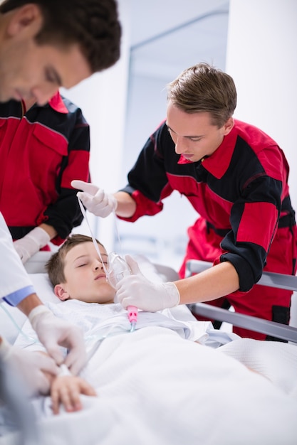 Foto gratuita medici che regolano la maschera di ossigeno mentre si precipitano il paziente in pronto soccorso