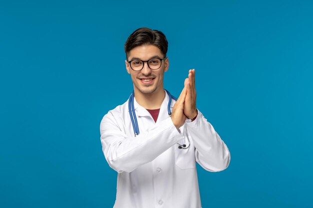 Doctors day handsome brunette cute guy in medical gown clapping hands in glasses