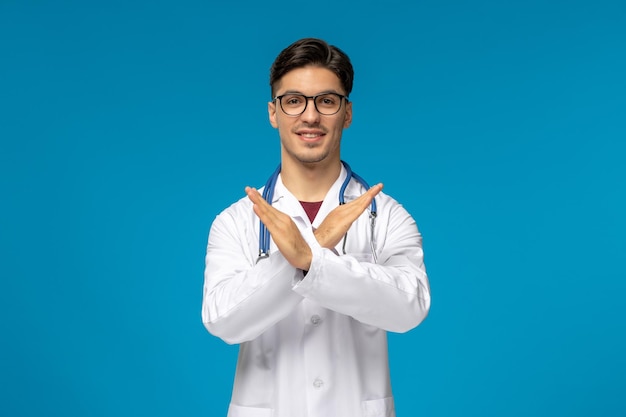 Doctors day handsome brunette cute guy in medical gown crossing hands