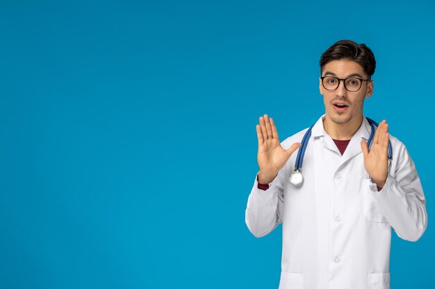 Doctors day handsome brunette cute guy in medical gown excited waving hands