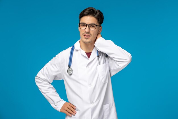Doctors day handsome brunette cute guy in medical gown holding neck wearing glasses