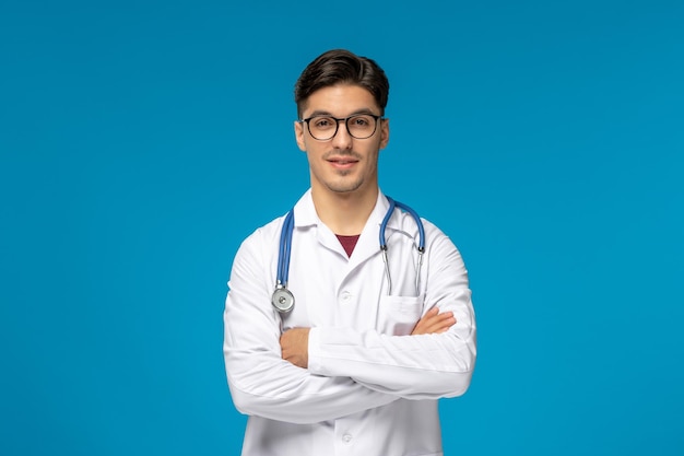 Doctors day handsome brunette cute guy in medical gown with crossed hands