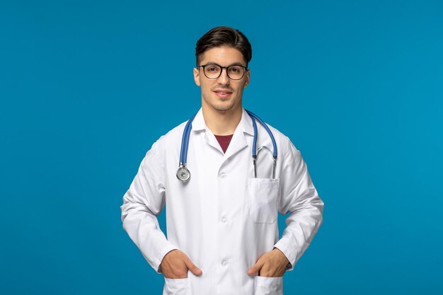 Doctors day handsome brunette cute guy in medical gown with hands in pocket