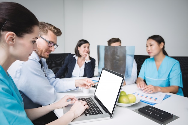 Doctors discussing over laptop in meeting