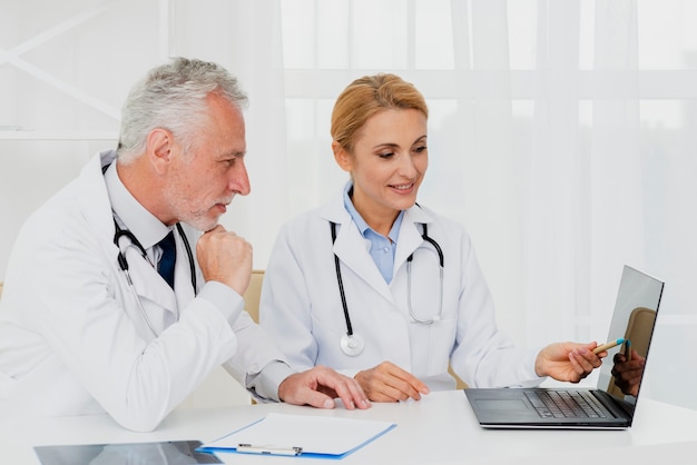 Free photo doctors looking at laptop while sitting