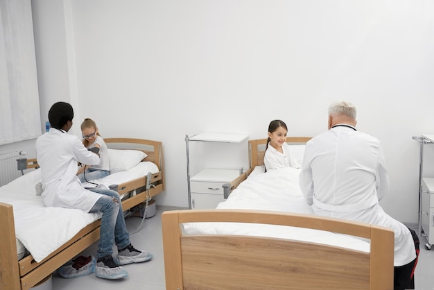 Free photo doctors measuring blood pressure of schoolgirls on couches