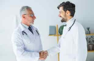 Free photo doctors shaking hands and looking at each other