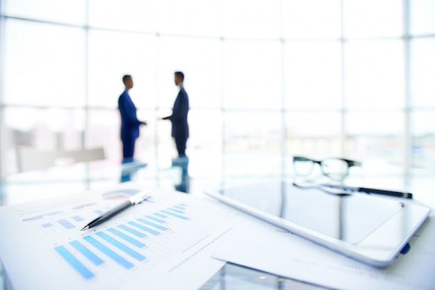 Documents with charts and a touchpad on the desk