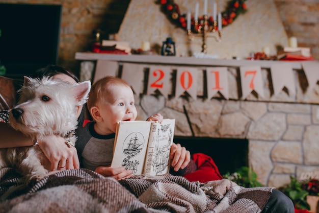 Dog next to baby having a book in hands