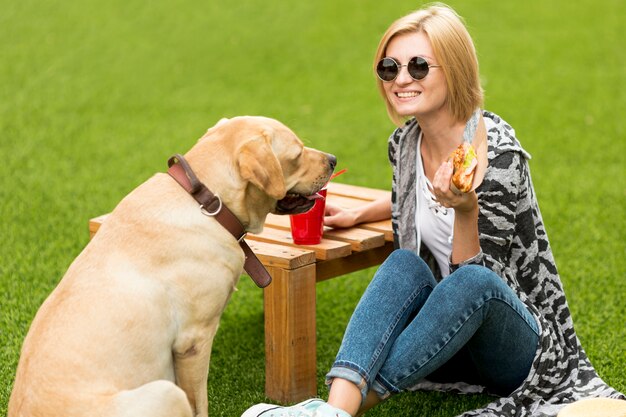 Dog looking at sandwich and woman smiling