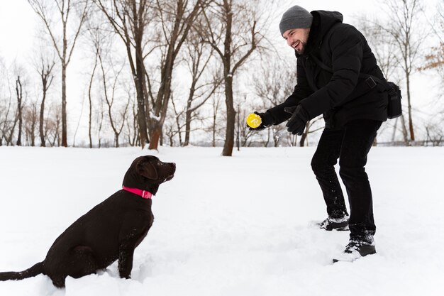 家族と雪の中で子供と遊ぶ犬