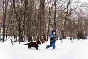 Foto gratuita cane che gioca con il bambino nella neve con la famiglia