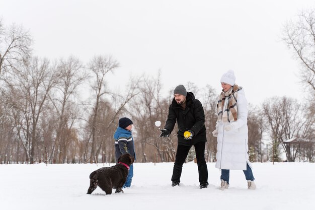 家族と雪の中で子供と遊ぶ犬