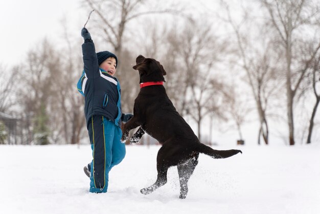 家族と雪の中で子供と遊ぶ犬