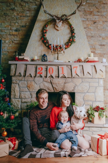 Free photo dog sitting on the wooden floor with a family background