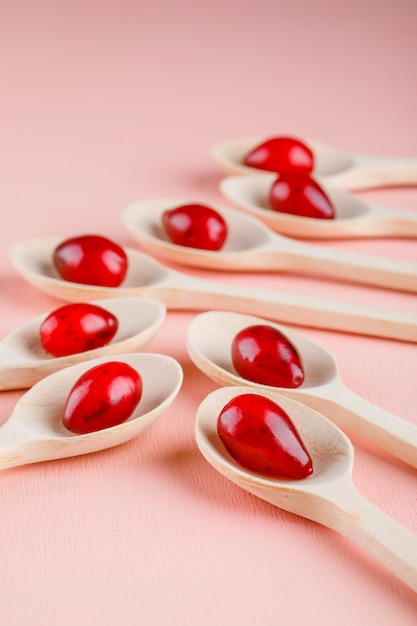 Dogwood berries in wooden spoons on pink. close-up.