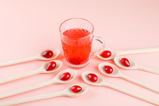 Dogwood berries in wooden spoons with drink high angle view on pink