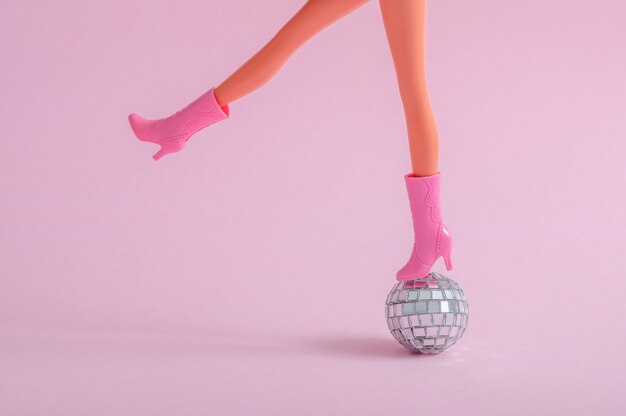 Кукольные ножки на маленьком диско-шаре на розовой стене