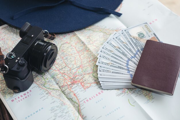 Долларовые банкноты, кредитная карта, паспорт, фотоаппарат и синяя шляпа