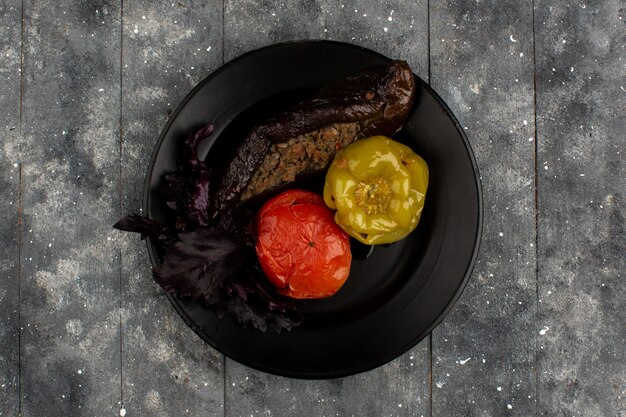 Dolma eastern meat dish with baked tomatoes eggplants and green bell peppers with meat minced meat inside black plate
