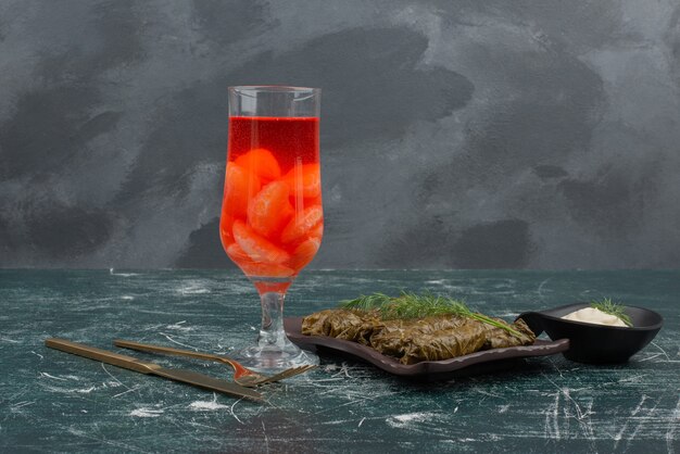 Dolma with glass of juice and sour cream on marble table .