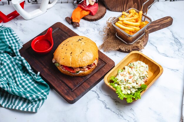 Doner in bread with ketchup on a board with french fries and a capital salad