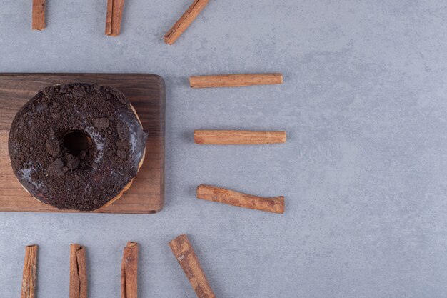 A donut and cinnamon sticks on marble surface