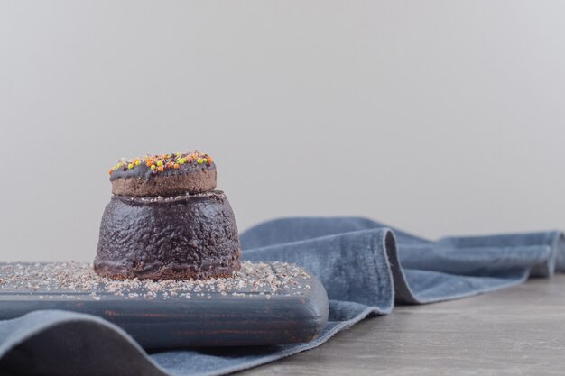 Donut on a small chocolate cake on a board on marble