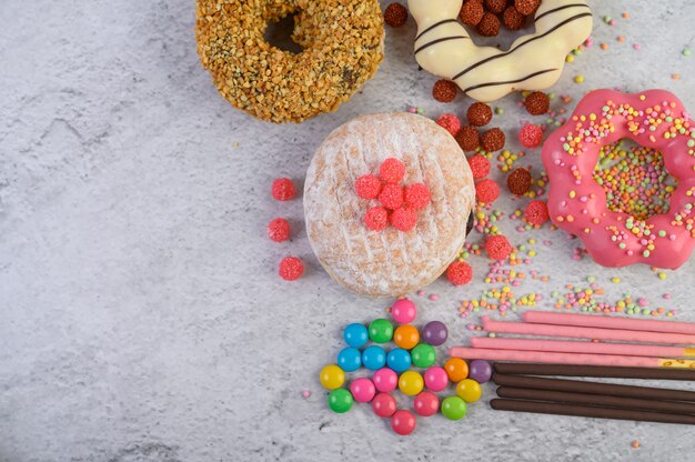 Donuts decorated icing and sprinkles on white surface top view