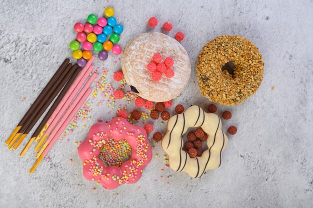 Donuts decorated icing and sprinkles on white surface top view