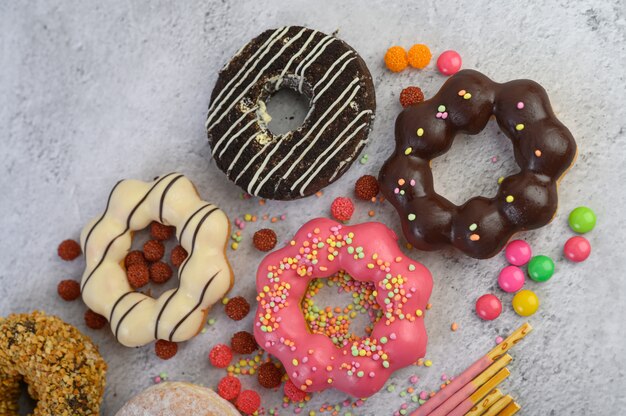 Donuts decorated icing and sprinkles on white surface top view