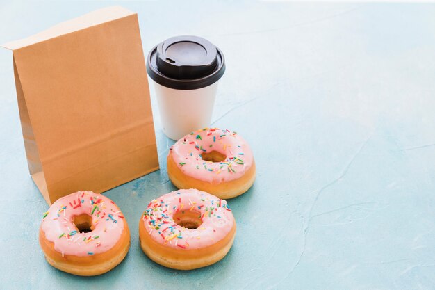 Donuts near package and disposal cup on blue background