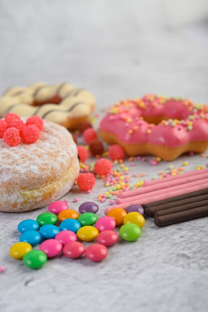 Donuts sprinkled with icing sugar and candy on a white surface.