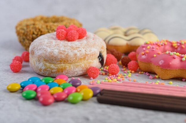 Donuts sprinkled with icing sugar and candy on a white surface.