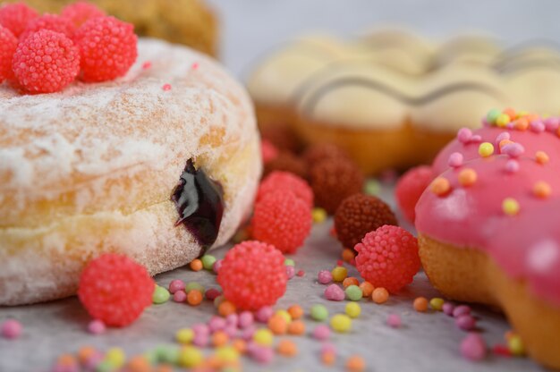 Donuts sprinkled with icing sugar and candy on a white surface.