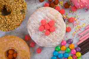 Free photo donuts sprinkled with icing sugar and candy on a white surface.