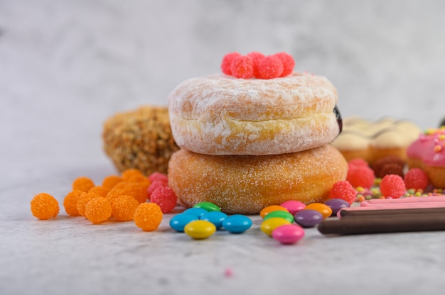 Donuts sprinkled with icing sugar and candy on a white surface.