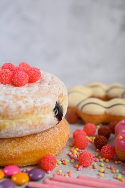 Donuts sprinkled with icing sugar and candy on a white surface.